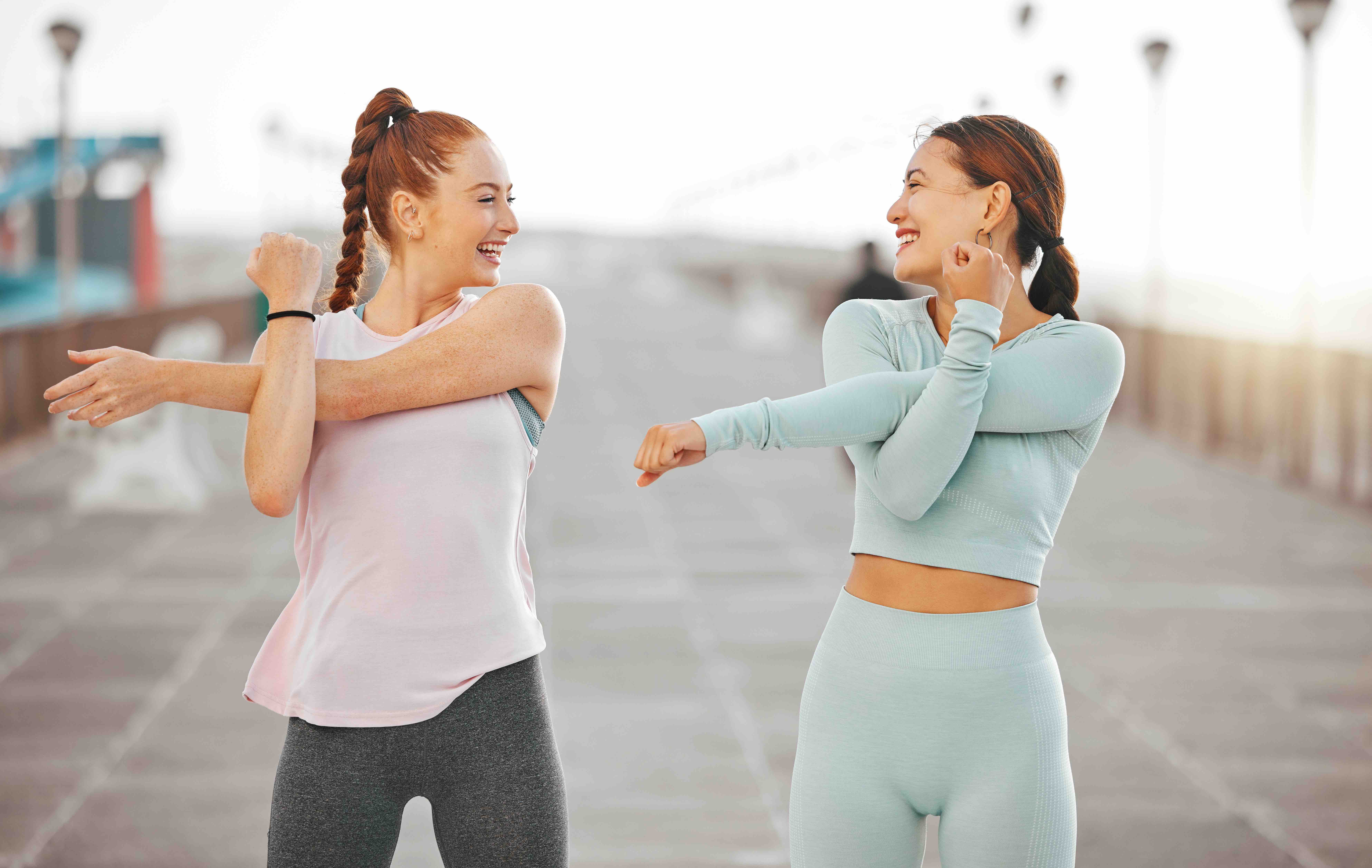 Fitness friends, exercise and wellness with two women stretching and warming up for their workout a.